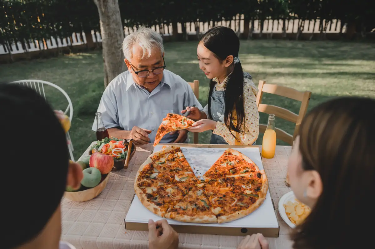 Family sharing pizza delivery in Singapore during a relaxed outdoor gathering