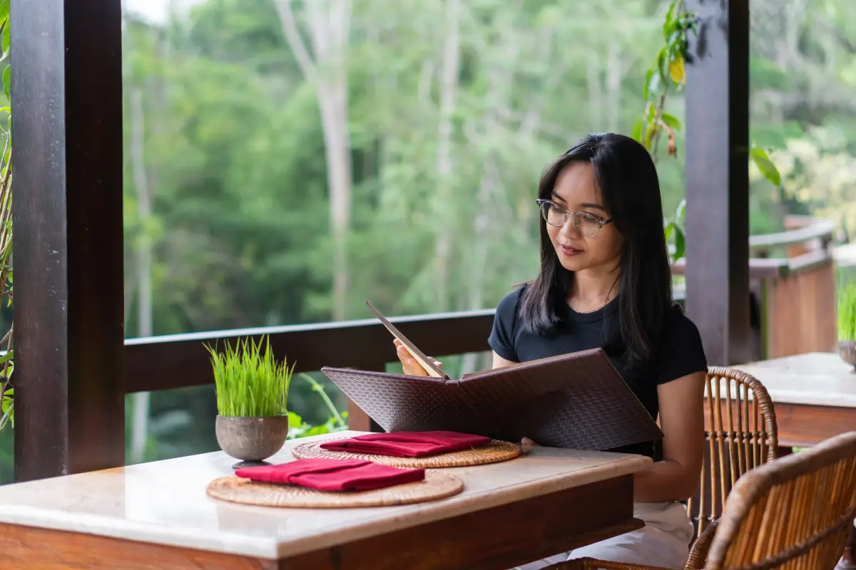 Customer reading a pizza menu while seated at a quiet outdoor restaurant